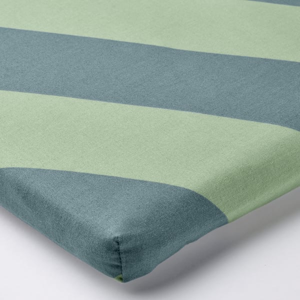 Hörn av randig grön och blå kudde, slät konsistens, ren design.