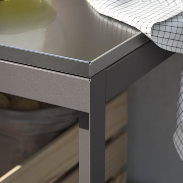 Modernt utekök med elegant bänkskiva i rostfritt stål och slitstarka pulverlackerade metallramar.