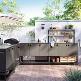 Modernt utekök med BÅTSKÄR-enheter, med ståldesign, bänk, grill, diskho, hyllor och grön inramning.