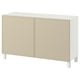 Ett vitt BESTÅ-sideboard med beige dörrar, rektangulär form och träben.