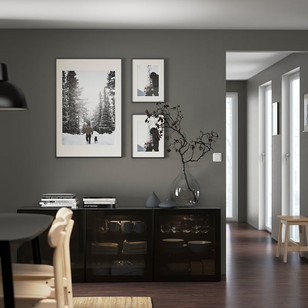 Modern matsal med svart BESTÅ-sideboard som visar tallrikar och vaser, minimalistiska möbler och konsttryck.