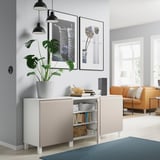 Modernt rum med BESTÅ vit skänk, krukväxt, orange soffa, lampor, böcker och inramad konst.