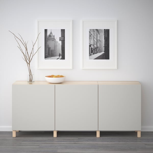 Modern skänk med svartvita foton och dekorativ skål. Två dörrar för förvaring.