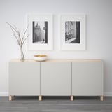 Modern skänk med svartvita foton och dekorativ skål. Två dörrar för förvaring.