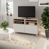 Modernt vardagsrum med BESTÅ-tv-enhet, platt-tv, böcker, dvd-skivor, blommor och växter.