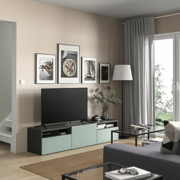 Modernt vardagsrum med tv-bänken BESTÅ, tv, grå soffa, soffbord, lampa och fönster med gardiner.