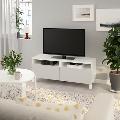 Modernt vardagsrum med tv-bänken BESTÅ, plattskärm, växter och matta.