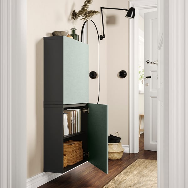 Öppna blå och svarta väggskåp med böcker och korgar, med en svart vägglampa.