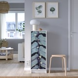 Modernt vardagsrum med lila väggar, bokhylla BILLY med mönstrad dörr, lampa, konst, pall, fönstervy.