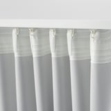 Tre vita gardiner hänger ihop, med en randig skir design upptill, som troligen blockerar ljus och reglerar temperaturen.