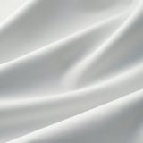 Närbild av slätt, glänsande vitt tyg, troligen högkvalitativa block-out-gardiner, som visar ljusreflektion och textur.