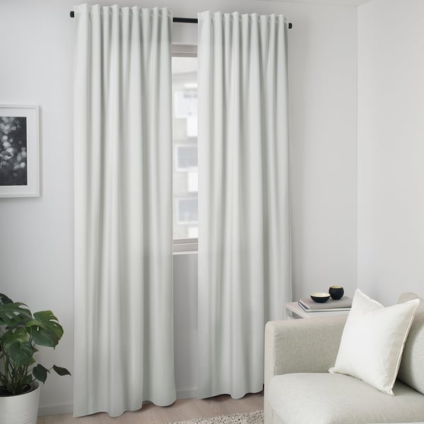 Modernt vardagsrum med vita BLYSPINNMAL blockoutgardiner, mjuk textur, täckande stort fönster, grädde soffa och liten växt.