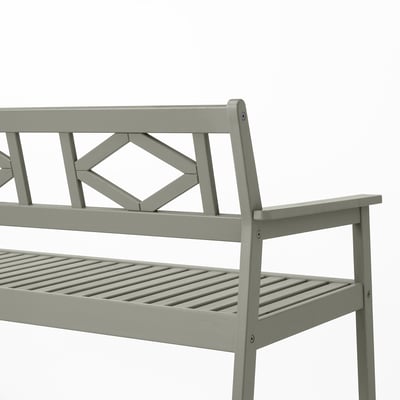 Ljusgrå utomhusbänk med intrikat ryggdesign, robust eukalyptusträ, lamellsits och armstöd, perfekt för komfort och hållbarhet.