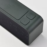 Modern digital väckarklocka med grön kropp, taktila kontroller och svagt upplysta siffror, designad för enkel avläsning och effektiv användning.