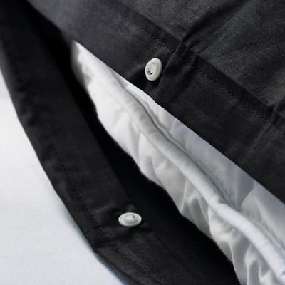 Svart örngott på vit yta. Mjukt bomullstyg av hög kvalitet, snyggt vikt, som visar slät struktur och hantverk.