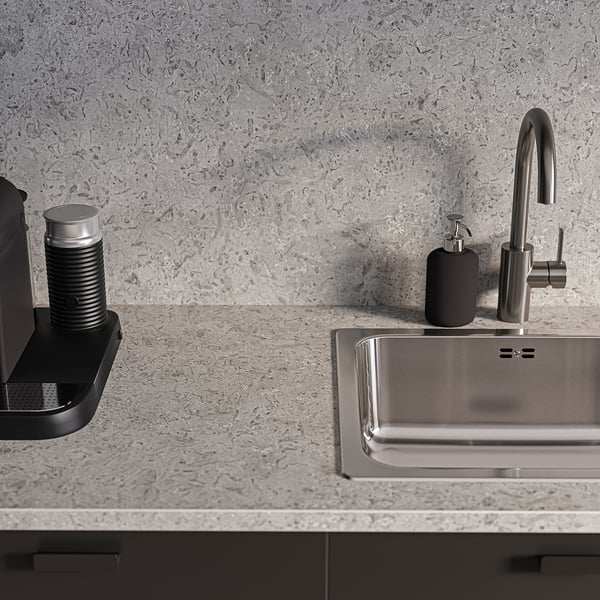Modern grå diskbänk med metallkran och tvålpump på texturerad stenmönstrad bänkskiva.