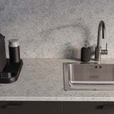 Modern grå diskbänk med metallkran och tvålpump på texturerad stenmönstrad bänkskiva.