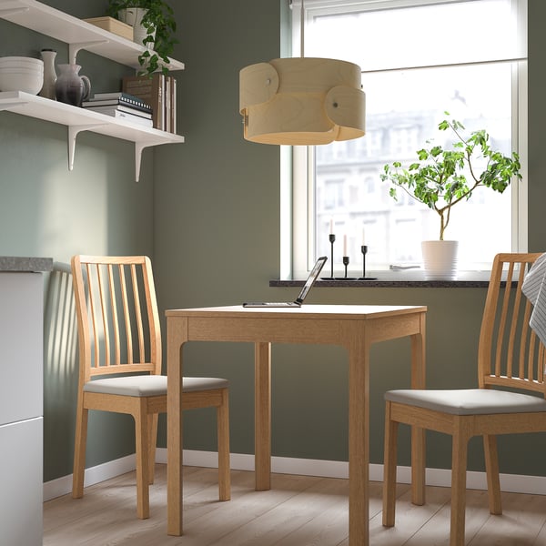 Mysig matplats med ett träbord, stolar, hyllor och en unik armatur.