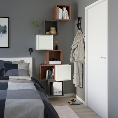 Modernt sovrum med hyllor i EKET, där öppen och stängd förvaring blandas, högt upp på väggen. Grå sängkläder fulländar den minimalistiska looken.