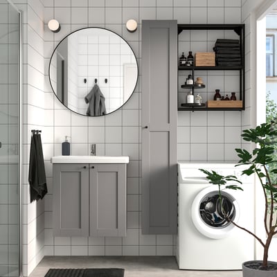 Modernt badrum med grå ENHET förvaring, spegel och vit tvättmaskin. Snygg, minimalistisk design.
