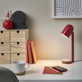 Röd ENSMÄRKE skrivbordslampa med träbotten, usb-c-port, bland böcker och anteckningsbok.