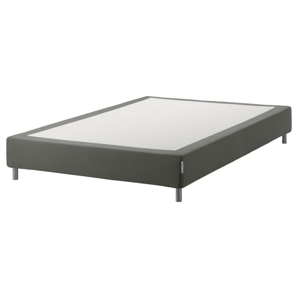 En espevar grå stoppad sängbotten med träribbor och metallben, designad för att stödja en madrass.