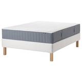 Blå och vit madrass på vit sängram med träben. IKEA-produkt.