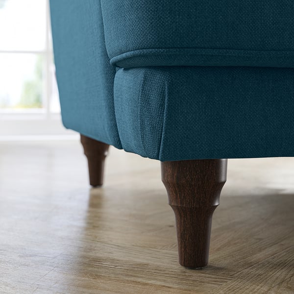 Bäddsoffa i blågrönt tyg, böjda ben. Mjuk, inbjudande design.