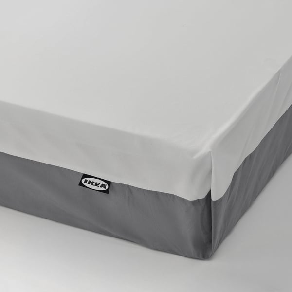Närbild av IKEA-madrass som visar kvalitetsdesign med grå sidor, vit topp och synlig varumärkesetikett.