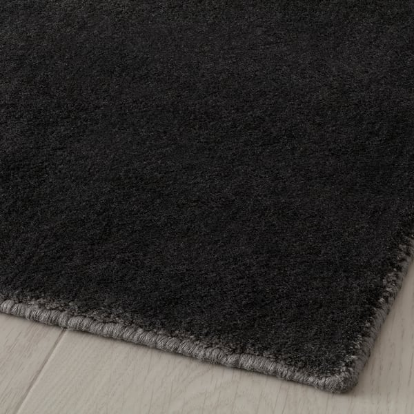 Mörkgrå mjuk matta med lätt glans, vikt på ljust trägolv.