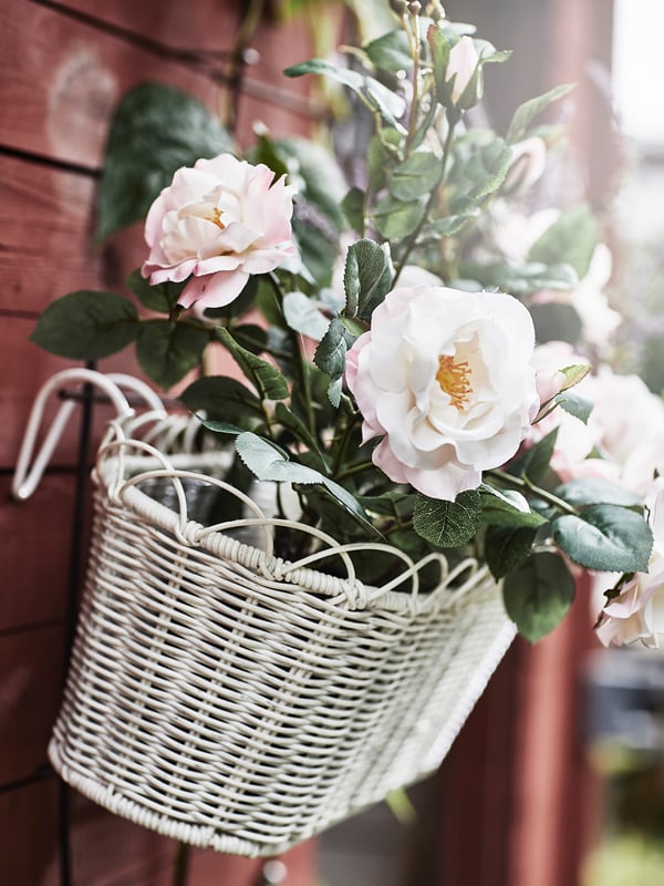 Korg med konstgjorda vita blommor på en vägg.