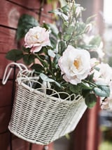 Korg med konstgjorda vita blommor på en vägg.
