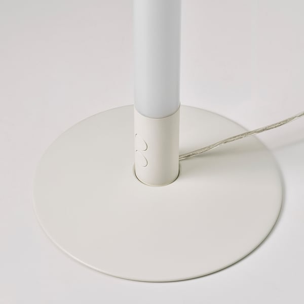 Modern vit golvlampa på nära håll, med slank design och rund bas.