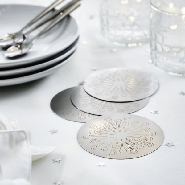 Eleganta glasunderlägg i rostfritt stål med fyrverkeridesign förhöjer bordsdekoren och är en del av kollektionen FRÖJDA.