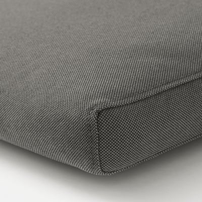 Närbild av en plysch, grå kudde med fina sömmar som framhäver det mjuka, strukturerade tyget.