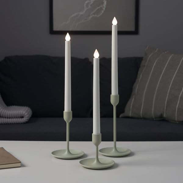 Tresiffra av olika höjd med tända ljus på ett bord nära soffan.
