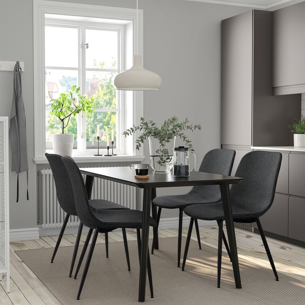 Minimalistisk matplats med svarta stolar, glasbord, naturligt ljus och återvunnet material.