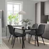 Minimalistisk matplats med svarta stolar, glasbord, naturligt ljus och återvunnet material.