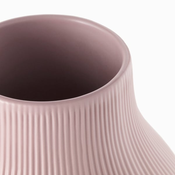 Närbild av en slät, ljusrosa vas GRADVIS med intrikata vertikala räfflor som framhäver dess eleganta struktur.