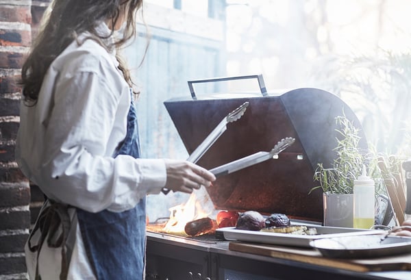 Kvinna grillar med GRILLSKÄR med tång.