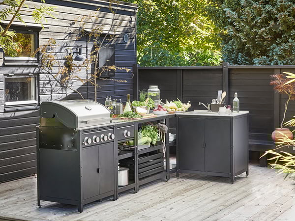 Modernt utekök: grill, bänk, diskbänk, färskvaror, växter, däck, elegant design.