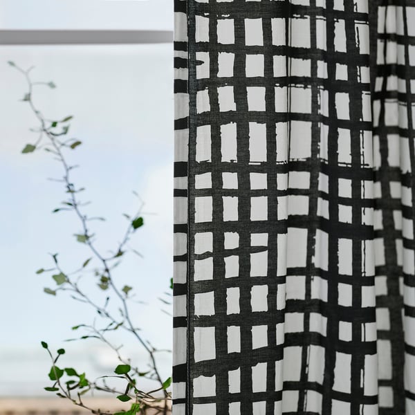 Svart- och vitrandig gardin hängs, filtrerande ljus, med synlig huvudtejp för enkla veck.