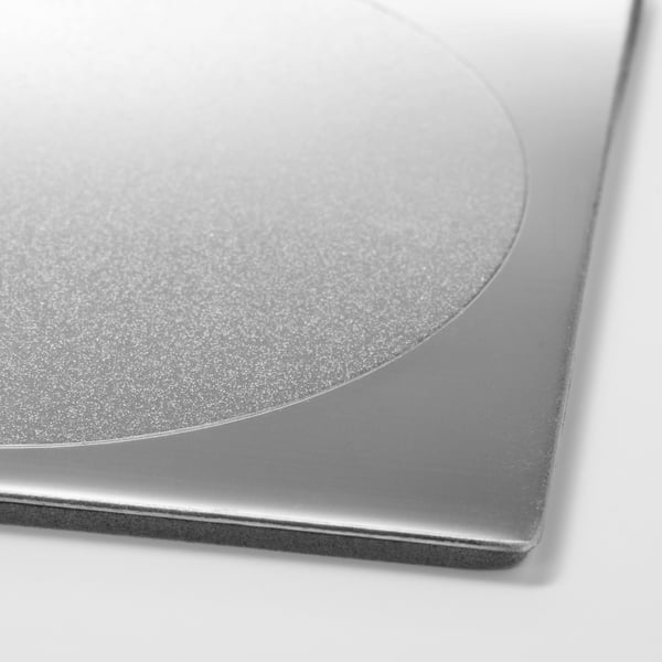 Elegant metalliskt underlägg i närbild, slät yta och böjda kanter.