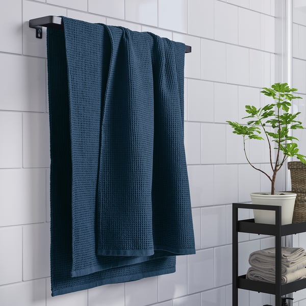 Blå handduk på ställ, återvunnen, snabbtorkar. Planta, vikta handdukar i närheten.