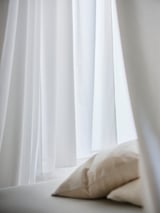 Vita ljudisolerade gardiner med ljusbeige kudde.