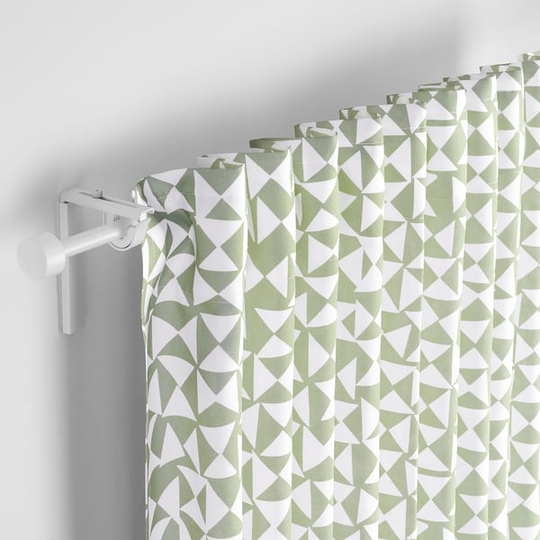 Geometriska grönvita gardiner hänger från en vit stång som filtrerar ljuset och ger avskildhet med en mönstrad design.