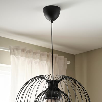 Från taket hänger en modern pendellampa med intrikat, vävd design och ger justerbar belysning.