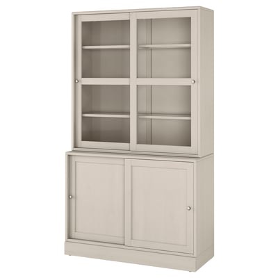 Ett ljusbeige HAVSTA förvaringsskåp. Det finns glasdörrar upptill och träskåp under. Designen är rustik med en finish i borstad furu.