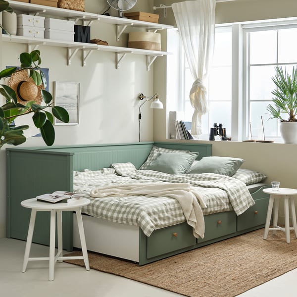 HEMNES grågrön dagbädd med förvaringslådor, omvandlas till en dubbelsäng, skummadrass, lackerad ram. Bredvid bord med växt, rumsinredning.