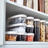 Hylla med stapelbara IKEA 365+ behållare som rymmer olika livsmedel, organiserade och väl synliga genom genomskinliga lock.